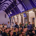 A busy audience sitting in chairs and standing at a pitching event
