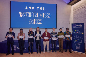 A group of students standing smiling with cheque prizes