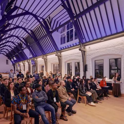 Attendees at a startup event sitting in rows of chairs watching pitches