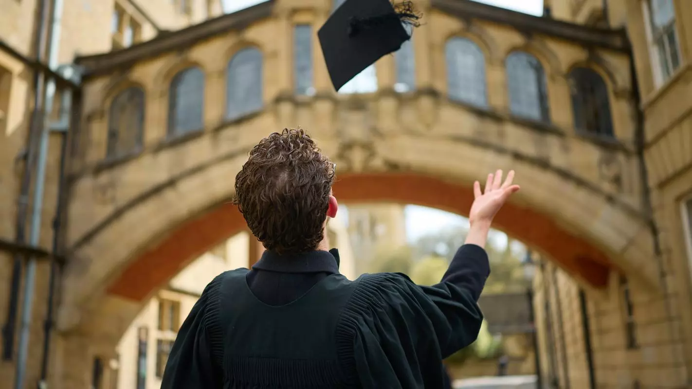 STUDENT CELEBRATING THE END OF AN EXAM BY TOSSING HIS MORTAR BOARD