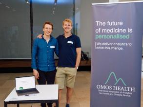 The Omos health team smiling and stood next to their stand
