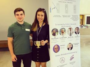 Demo Night 2023 first place winners, Gambit Bio stood next to their stand holding a trophy